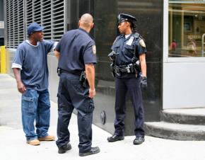 NYPD cops hassle a man on a corner in the Bronx